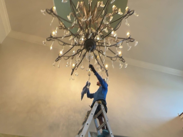A Sapphire technician on a ladder cleaning a chandelier