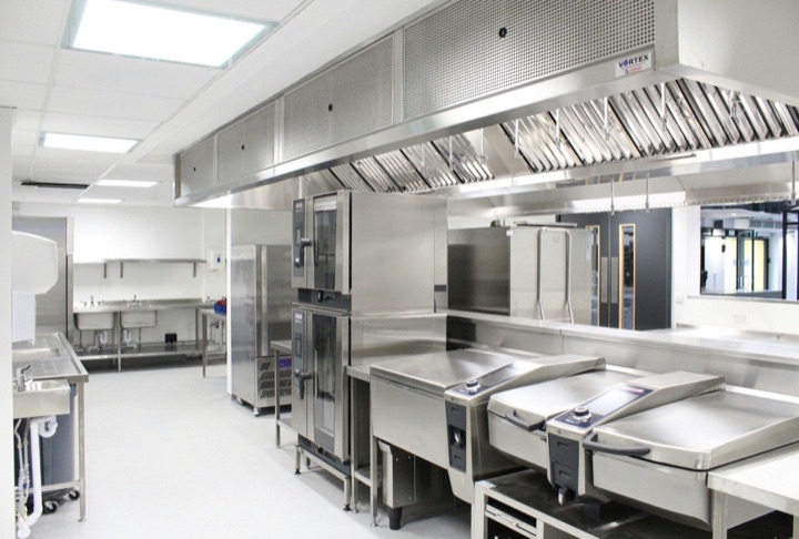 A clean stainless steel exhaust hood with baffle filters in a commercial kitchen