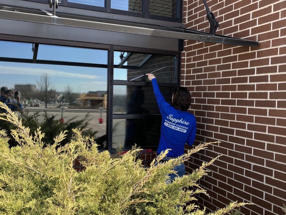 A Sapphire technician cleaning windows on a brick building